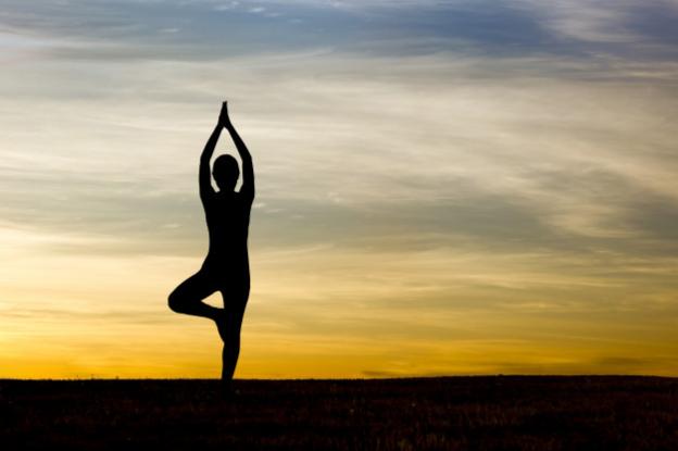 Silhouette of woman practicing yoga at sunrise Premium Photo
